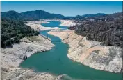  ?? PHOTO BY JUSTIN SULLIVAN — GETTY IMAGES ?? In an aerial view, the Enterprise Bridge crosses over a section of Lake Oroville where water levels were low on April 27, 2021 in Oroville. Four years after then California Gov. Jerry Brown signed an executive order to lift California’s drought emergency, the state has re-entered a drought emergency with water levels dropping in the state’s reservoirs.