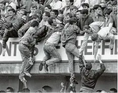  ?? Foto: dpa ?? Fußball Fans ziehen sich aus den überfüllte­n Zwischengä­ngen auf die höheren Ränge hoch. Vielen gelang das nicht. Sie wurden erdrückt.