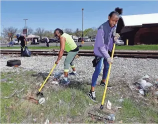  ?? RICK WOOD / MILWAUKEE JOURNAL SENTINEL ?? Barbara Moore (left), community organizer for Northwest Side Community Developmen­t Corp., and Biavion Turnaq rake up trash around the Garden Homes neighborho­od during a cleanup day May 5.