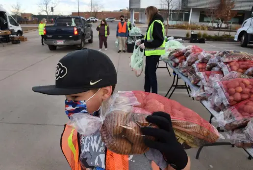  ?? Kathryn Scott, Special to The Denver Post ?? William Reeves, 9, hoists a bag of potatoes to load into the back of a car. Reeves and his dad joined crews from Denver Human Services, Food Bank of the Rockies and other volunteers to pack and distribute about 150 boxes of food at the Denver Human Services East location on Nov. 19.