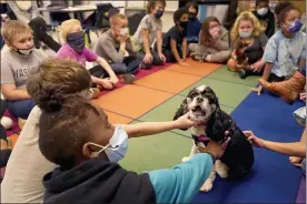  ?? CHARLIE RIEDEL - THE ASSOCIATED PRESS ?? Tillie the therapy dog sits among third graders at Quincy Elementary School, Nov. 3, in Topeka, Kan. The dog is one of the tools designed to relieve stresses faced by students as they return to classrooms amid the ongoing pandemic.