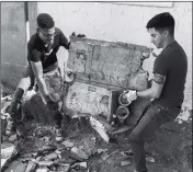  ??  ?? Cpl. Isaac D. Martinez and Lance Cpl. Joel Soriano move a large piece of rubble from a torn-down shed at St. Thomas Yuma Indian Mission.