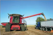  ?? JOSHUA A. BICKEL / AP ?? A combine (left) unloads soybeans onto a trailer during harvest on Oct 10 at a farm in Illinois, the United States.