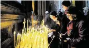  ?? Olga Maltseva / AFP/ Getty Images ?? Russians light candles for the Oct. 31 crash victims Sunday at St. Isaac’s Cathedral in St. Petersburg.