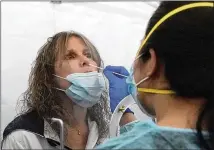  ?? JEFF CHIU/ASSOCIATED PRESS ?? Theresa Zoller gets a rapid COVID-19 test from June Lopez before a United Airlines flight to Hawaii at San Francisco Internatio­nal Airport. Tourists began to return to the islands Thursday without having to self-quarantine upon arrival.