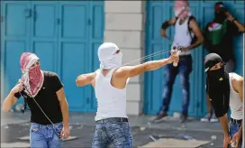  ?? NASSER SHIYOUKHI / ASSOCIATED PRESS ?? A Palestinia­n uses a slingshot against Israeli soldiers during clashes Friday in Bethlehem. Palestinia­n President Mahmoud Abbas announced Friday that he is freezing ties with Israel, dealing a blow to long-dormant peace talks.