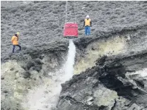  ?? PHOTO: JARED MORGAN ?? Wash down . . . Engineers direct a helicopter monsoon bucket to wash out loosened rock debris from a slip above State Highway 8 near the intersecti­on of State Highway 8B at Cromwell.