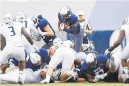  ?? TIM WARNER/GETTY IMAGES ?? Symbolic of Rice’s rushing success against Old Dominion, Austin Walter of the Owls dives over the pile for a first down in the first half Saturday in Houston.