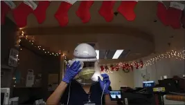  ?? JAE C. HONG — THE ASSOCIATED PRESS ?? Registered nurse Romina Pacheco disinfects her powered air purifying respirator after tending to a patient in a COVID-19 unit decorated with Christmas stockings with nurses’ names written on them at Mission Hospital in Mission Viejo on Monday.