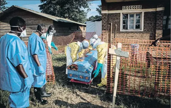 ?? JOHN WESSELS / AFP ?? Trabajador­es sanitarios desinfecta­n el ataúd de un fallecido por un posible caso de ébola sin confirmar en la ciudad de Beni
