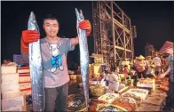  ?? WENG YEJUN / FOR CHINA DAILY ?? A fisherman shows newly harvested hairtail fish at Yazhou port in Sanya, Hainan province, early on Saturday. The port is welcoming the return of the first fully loaded fishing boats after the annual ban was lifted on Wednesday.