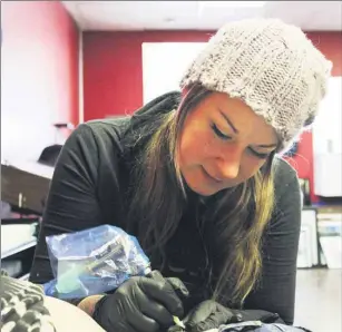  ?? CODY MACKAY/THE GUARDIAN ?? Griffen Dunsmore of Artist’s Ink in Summerside, works away tattooing a butterfly on one of her client’s lower back recently.