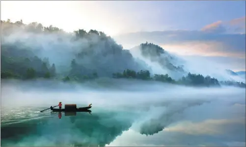  ?? PROVIDED TO CHINA DAILY ?? Shrouded in morning mist, a boatman navigates Dongjiang Lake in Zixing city, regarded as the top attraction in southern Hunan.
