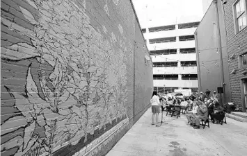  ?? STEPHEN M. DOWELL/ORLANDO SENTINEL ?? A new mural titled “Land of Merchants” is unveiled during a ceremony in the alley next to the CityArts gallery in Orlando on Thursday. It’s the first in a series of “placemakin­g” installati­ons planned for throughout downtown and the first step in transformi­ng the alleyway into an outdoor extension of the art gallery.