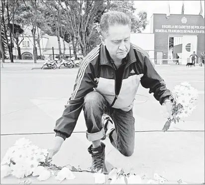  ??  ?? Un hombre coloca flores en un altar improvisad­o frente a la Academia de Policía General Francisco de Paula Santander, en Bogotá, un día después de que un coche bomba explotara en el lugar. Foto Ap