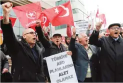  ??  ?? ANKARA: Protesters shout slogans against US strike on an airbase of the Syrian regime as they hold Turkish flags and placards reading ‘Turkey cannot be an instrument of US’ in front of the US Embassy in Ankara yesterday. — AFP