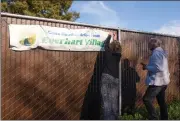  ?? MICHAEL WEBER — ENTERPRISE-RECORD ?? Chico Housing Action Team Executive Director Nicole Drummond, left, fixes a banner with volunteer Robert Trausch on Wednesday at the Everhart Village project site in Chico.