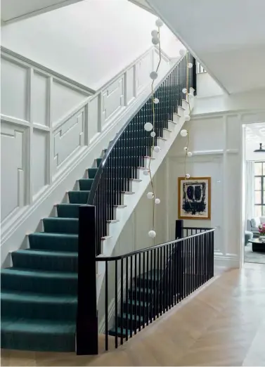  ??  ?? Left to right: Set against elegant wall mouldings is a custom fireplace made of Breccia Capraia marble; a pair of bespoke Lindsey Adelman chandelier­s add character to the stairwell; curved furnishing­s such as this sofa from Vladimir Kagan balance the angular lines of the mouldings and shelves
Previous spread: The living room features ornamental plasterwor­k and full-length windows that overlook the outdoor garden