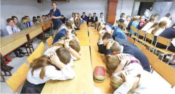  ?? — AFP ?? Schoolchil­dren cover their heads with their hands as they take part in security exercises in a school in the Kiev-controlled village of Sartana, Donetsk region.