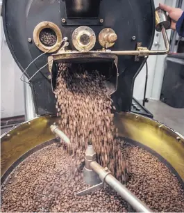  ??  ?? Coffee beans spill out of a roaster inside the Villa Myriam warehouse.