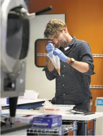  ??  ?? Senior scientist Haney takes a sample of water rinsed from chicken skin to do an analysis at Clear Labs.