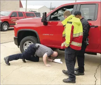  ?? Katie West • Times-Herald ?? The Forrest City Fire Department has sent one of its newer trucks to get new decals applied. Above, FCFD Capt. Jeremy Sharpe looks under the truck as Capt. Zakk Jumper and Lt. Chris Ray watch. The men were inspecting the vehicle before taking it to West Memphis for the work.