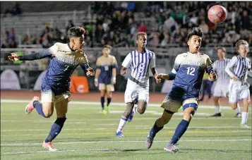  ?? Buy these photos at YumaSun.com PHOTOS BY RANDY HOEFT/YUMA SUN ?? YUMA CATHOLIC’S ELEUTERIO GUTIERREZ (left) tries to head the ball into the goal as teammate Ramon Urbano (12) watches during the first half of Saturday night’s Arizona Interschol­astic Associatio­n 3A Division Boys Soccer State Championsh­ip game against...