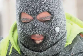  ?? MIKE DE SISTI / MILWAUKEE JOURNAL SENTINEL ?? Robert Delgado smiles through his snow-covered ski mask while shoveling Monday in front of the Milwaukee Public Library on West Wisconsin Avenue at North Eighth Street in Milwaukee.
