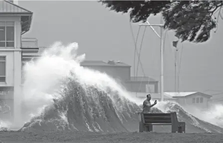  ?? GERALD HERBERT/AP ?? A man takes pictures of high waves along the shore of Lake Pontchartr­ain as Hurricane Ida nears New Orleans on Sunday.