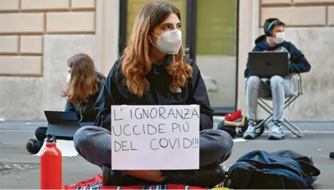  ?? Foto: Johannes Neudecker, dpa ?? „Unwissenhe­it tötet mehr als Covid“steht auf dem Zettel, den diese Schülerin an ihrem Laptop befestigt hat. Sie sitzt mit Klassenkam­eraden vor ihrem Gymnasium in Rom auf der Straße.