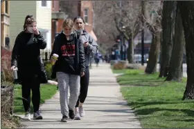  ?? (AP/Nam Y. Huh) ?? People take a walk Saturday in Chicago, a city that has largely been shut down to slow the spread of the coronaviru­s.