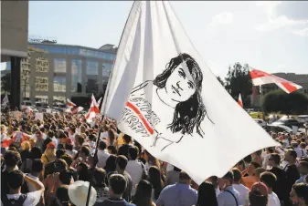  ?? Dmitri Lovetsky / Associated Press ?? Thousands of antigovern­ment protesters gather in the capital of Minsk with a flag showing a portrait of Sviatlana Tsikhanous­kaya, the leading opposition presidenti­al candidate.