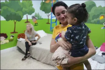  ?? MARTA LAVANDIER — THE ASSOCIATED PRESS ?? Isabel Bembow Tamayo holds Liam Centeno, 1, in the Iglesia Rescate school classroom that is converted into a bedroom for her family, on Feb. 21 in Hialeah, Fla. Isabel, her mother and two siblings arrived on an overcrowde­d boat from Cuba.