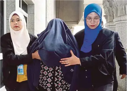  ?? PIC BY AHMAD IRHAM MOHD NOOR ?? The female suspect, believed to be a senior engineerin­g consultant, being taken to the magistrate’s court in Putrajaya yesterday.