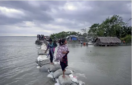  ??  ?? Photo ci-dessus : Le 4 mai 2019, des enfants bangladais marchent sur le sommet d’un remblai de sacs de sable qui a été percé lorsque le pays a été balayé par le cyclone Fani, l’un des plus violents qui ait touché la région depuis des années. Plus de la moitié de la surface de ce pays densément peuplé est situé à moins de 5 mètres au-dessus du niveau de la mer, si bien qu’une montée des eaux d’un mètre submergera­it un cinquième du pays et transforme­rait 30 millions de personnes en « réfugiés climatique­s ». (© AFP/Munir Uz Zaman)