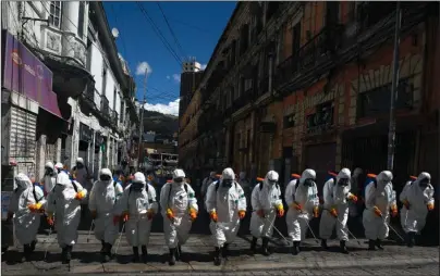  ?? The Associated Press ?? FUMIGATION: City workers fumigate a street to help contain the spread of the new coronaviru­s on Thursday in La Paz, Bolivia.