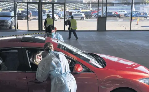  ?? AFP ?? A member of the Australian Defence Force takes a swab for a Covid-19 test from a member of the public at a drive-through testing station in Melbourne on Monday.