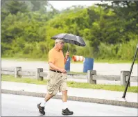  ?? Arnold Gold / Hearst Connecticu­t Media ?? Mike Kupson carries an umbrella on Friday during his daily 2-mile walk near Gulf Beach in Milford.