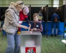  ?? Mindaugas Kulbis/Associated Press ?? A woman with children casts a ballot at a polling station Sunday during the first round of voting in presidenti­al elections in Vilnius, Lithuania.