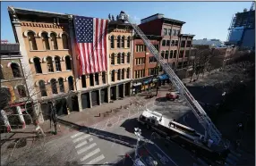  ??  ?? Firefighte­rs unfurl an American flag Monday on the street where a Christmas Day bombing took place in Nashville, Tenn. Officials are continuing to assess the damage to dozens of buildings after the explosion in downtown Nashville’s historic district.