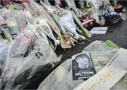  ?? EMILIO MORENATTI THE ASSOCIATED PRESS ?? A photo of police Lt. Col. Arnaud Beltrame rests on flowers at the main gate of the police headquarte­rs in Carcassonn­e, France. Beltrame, who offered himself up to an Islamic extremist attacker in exchange for a hostage on Friday, died of his injuries.