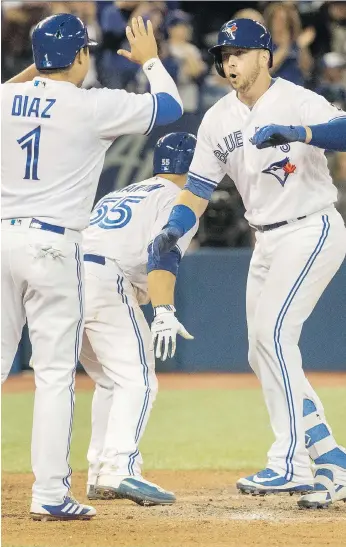  ?? PHOTOS: FRED THORNHILL/THE CANADIAN PRESS ?? Toronto Blue Jays first baseman Justin Smoak is greeted at home plate by teammates Aledmys Diaz and Russell Martin after his grand slam against New York Yankees reliever David Robertson in the eighth inning in Toronto on Sunday. It was Smoak’s second...