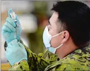  ?? SARAH GORDON/THE DAY ?? Hospital Corpsman Roberto Berry fills a dose of the Moderna mRNA-1273 vaccine during a COVID-19 vaccinatio­n clinic Wednesday at the Naval Submarine Base’s Morton Hall Gymnasium in Groton.