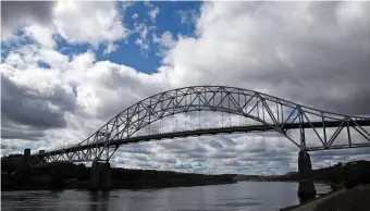  ?? MATT sTONE pHOTOs / HERALd sTAFF FILE ?? GETAWAY ROUTE: Traffic transits the Sagamore Bridge over the Cape Cod Canal. Tourism officials and business owners hope to cash in despite the coronaviru­s, but the pandemic is expected to leave a significan­t mark. Below, beachgoers find plenty of room at Craigville in a June lull last year.