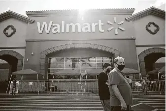  ?? Patrick T. Fallon / Bloomberg ?? Shoppers wearing protective masks walk outside a Walmart store in Torrance, Calif. The rule requiring masks also is going into effect at the company’s Sam’s Club stores.