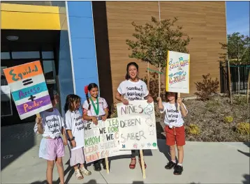  ?? PHOTOS BY JENNIE BLEVINS — ENTERPRISE-RECORD ?? Rosedale Elementary School Assistant Principal and Equity Leader Joana Campos, who was recently let go of her position, stands with some young protesters outside the Chico Unified School District School Board meeting Wednesday at Marigold Elementary School in Chico.