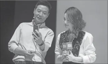  ?? FENG YONGBIN / CHINA DAILY ?? Lei Jun, CEO of Xiaomi Corp, tries Redmi Pro, a new Xiaomi handset released on Wednesday in Beijing, while actress Liu Shishi looks on.
