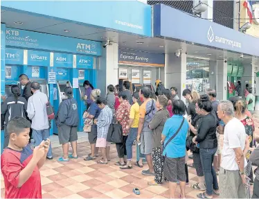  ?? SAROT MEKSOPHAWA­NNAKUL ?? Welfare cardholder­s queue at a Krungthai Bank near Poonsap market in Pathum Thani to withdraw 500 baht the government deposited as a New Year’s gift for low-income earners.