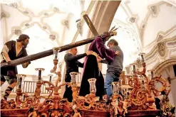  ?? ?? Members of the Nuestro Padre Jesús Nazareno brotherhoo­d adjust the esparto belt of the statue of Christ on top of a weighted structure, known traditiona­lly as ‘paso’, in preparatio­n for Holy Week procession­s.