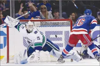  ?? The Associated Press ?? New York Rangers forward Jimmy Vesey, right, scores past Vancouver Canucks goaltender Jacob Markstrom during third-period NHL action on Sunday in New York.